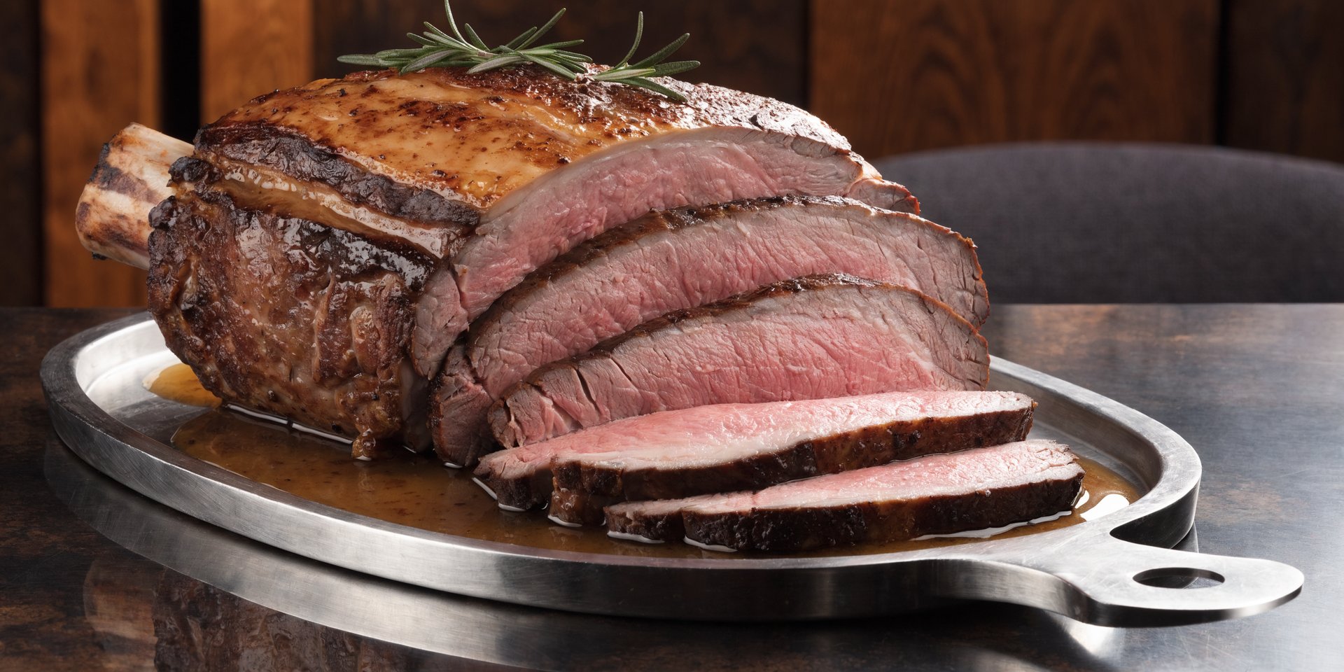 A thick slice of prime rib shows a consistent medium-rare pink from edge to edge with a golden-brown crust.