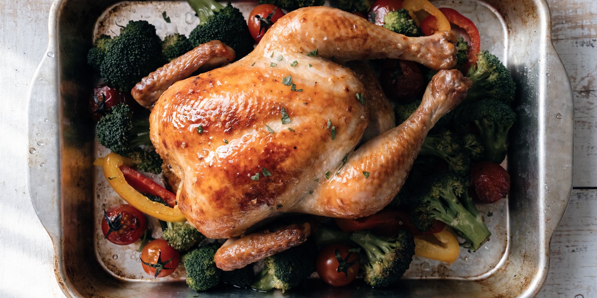 Roasted chicken with broccoli, bell peppers, and tomatoes on a sheet pan